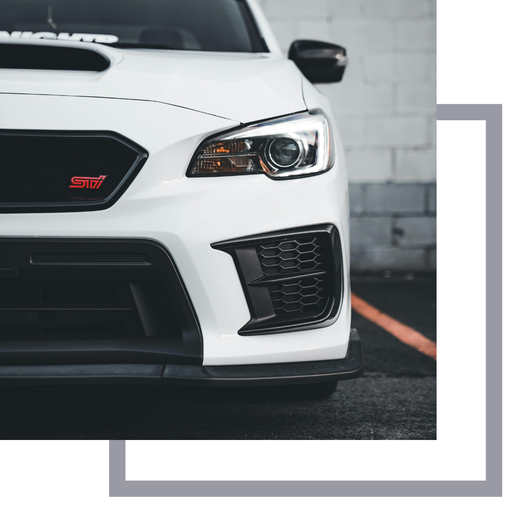 Grill of a white Subaru STI with red logo