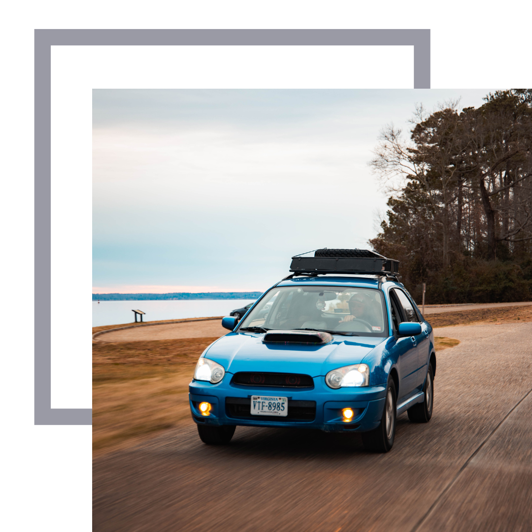 Blue Subaru driving by a lake